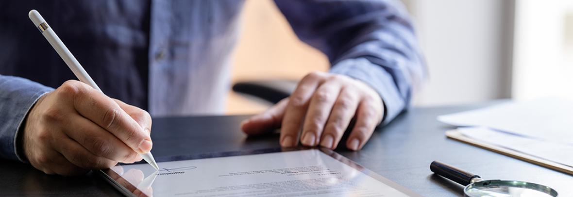 Photo of a man signing a contract on a tablet computer