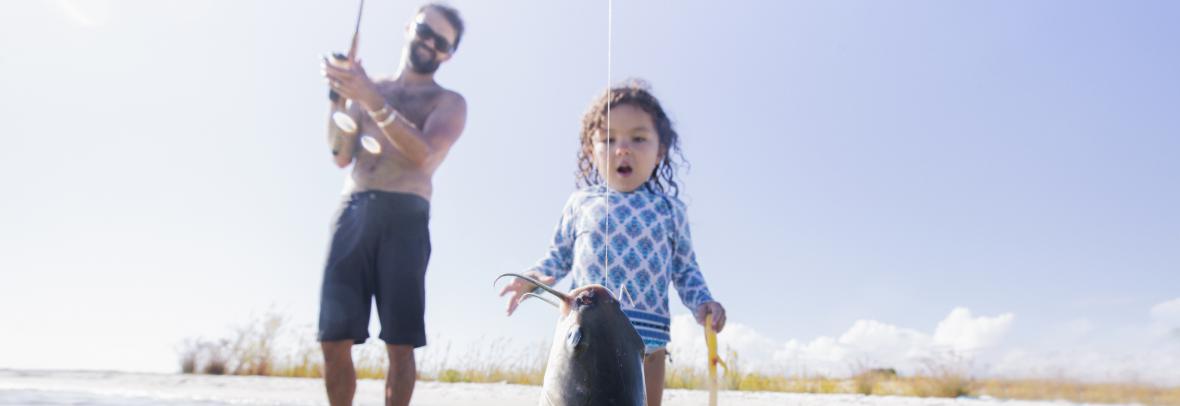 Toddler stares in amazement as father catches a fish