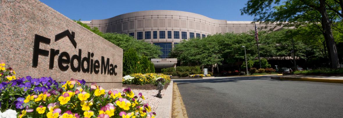 Front sign of Freddie Mac building in Virginia. Sign is surrounded by flowers and a blue sky