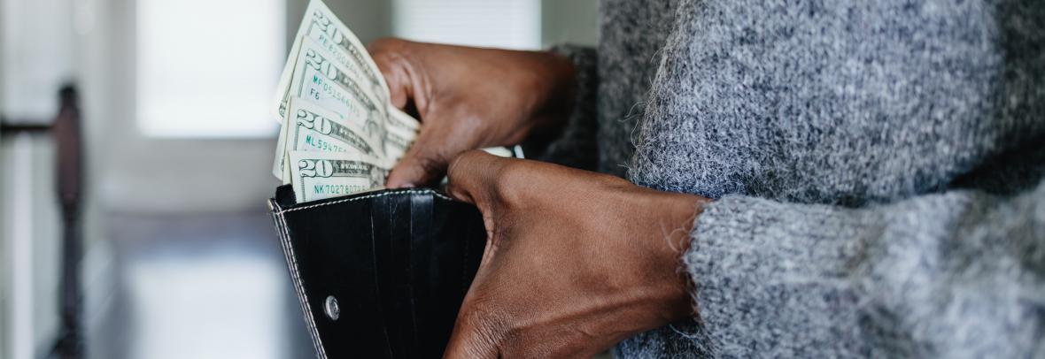 hands holding wallet filled with cash