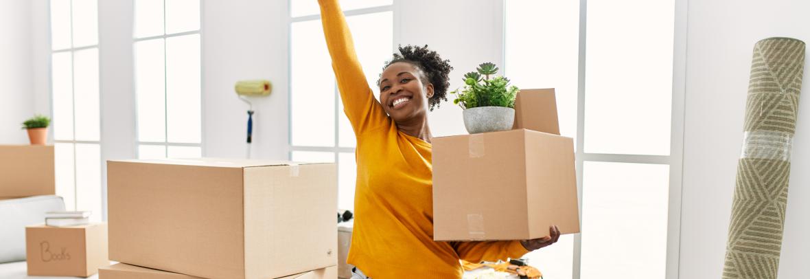 smiling woman unpacking boxes, happy with one arm raised in victory