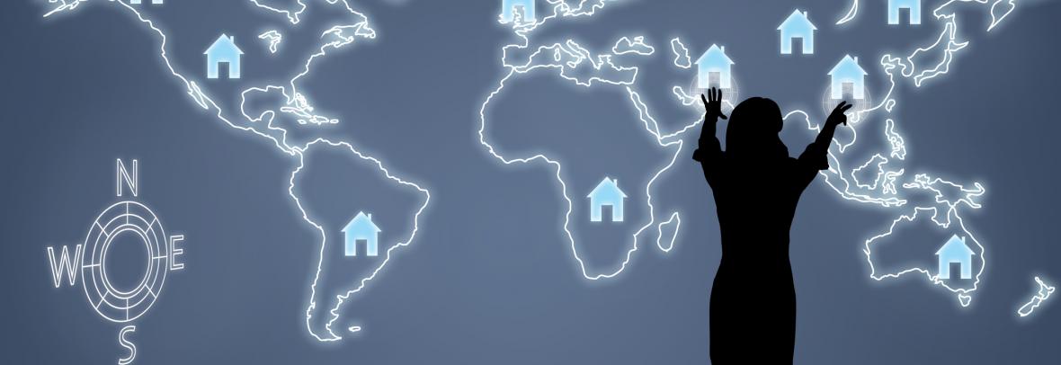 woman standing in front of digital world map with house logos
