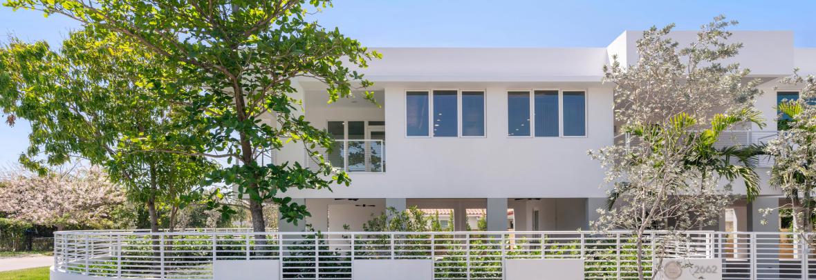 image of healthy sustainable home built in florida. white block-shaped home with trees in front 