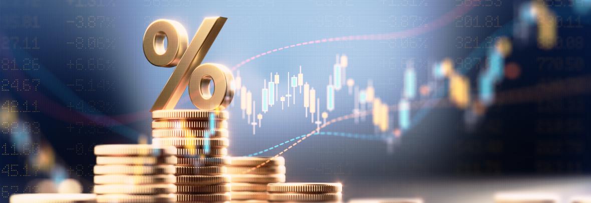Percentage sign on top of coin stacks before blue financial graph. Horizontal composition with copy space. Business and finance concept.
