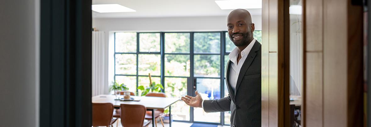 Photo of a black, male real estate agent opening a front door