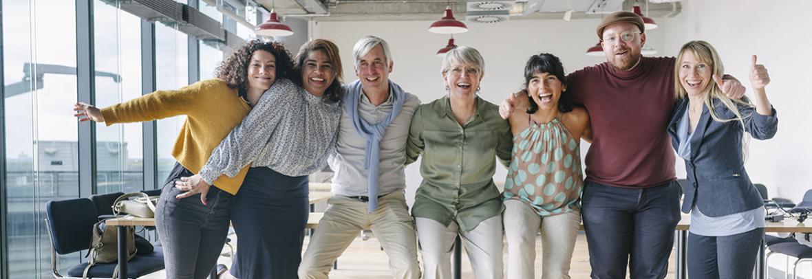 Photo of team of business people with arms around each others shoulders