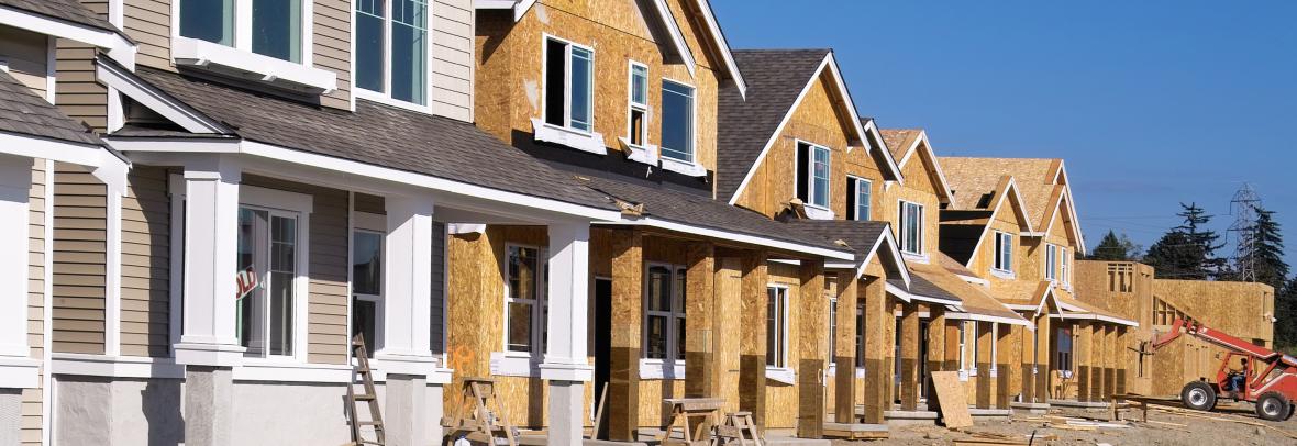 Housing Development Under Construction - stock photo Perspective photo of a row of similar style houses during various phases of construction.
