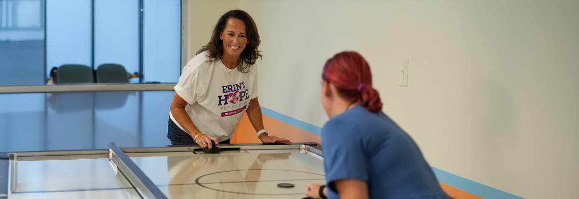 Stacy Horst plays table hock with a young adult 