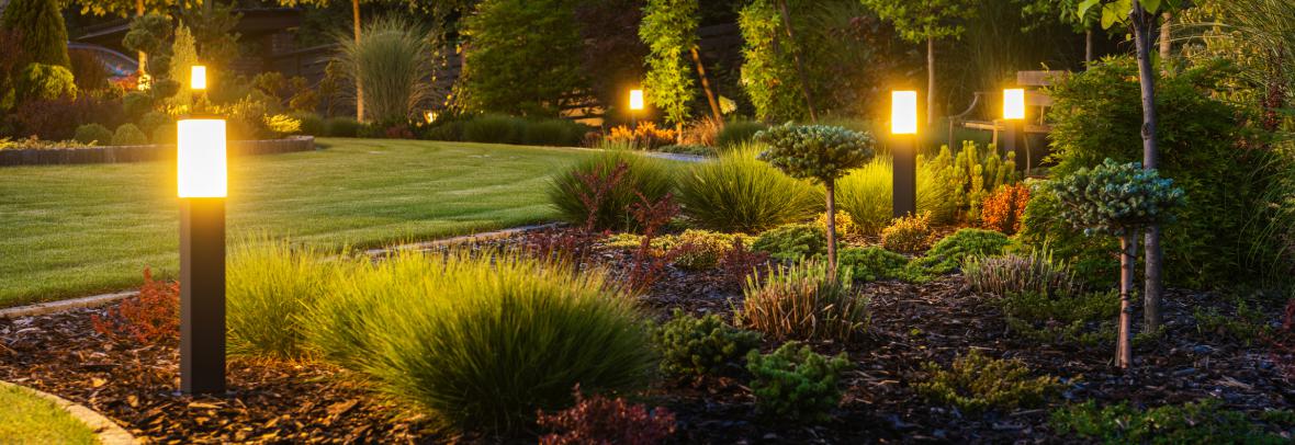 Modern Backyard Outdoor LED Lighting Systems - stock photo Panoramic Photo of LED Light Posts Illuminated Backyard Garden During Night Hours. Modern Backyard Outdoor Lighting Systems.