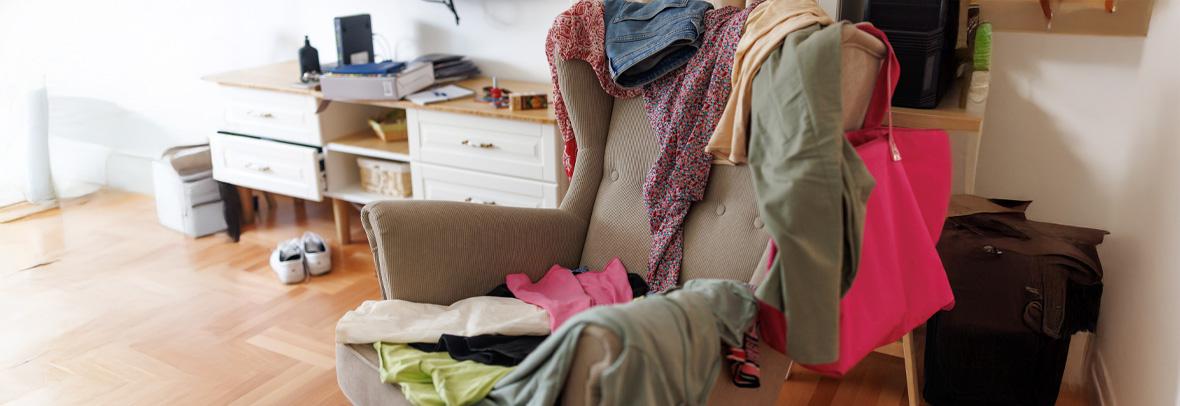 Messy room with scattered clothes on the armchair without people