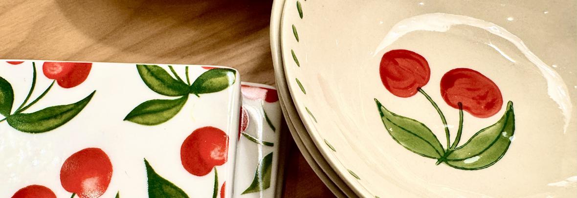 Food bowls and coasters with a cherry theme on a wooden table -