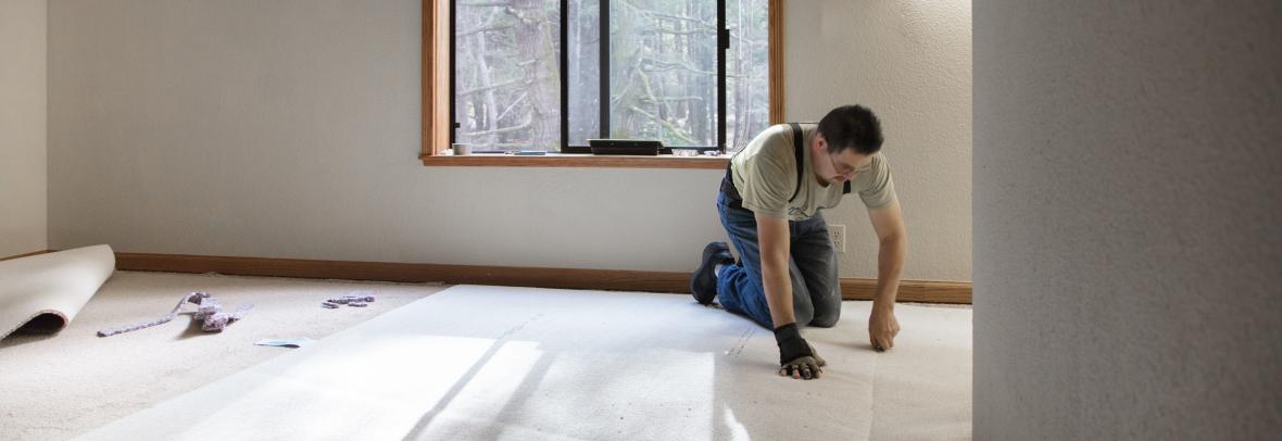 Man installing carpeting in home.