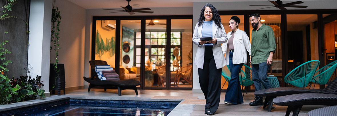 Photo of realtor showing couple a luxury home and pool deck