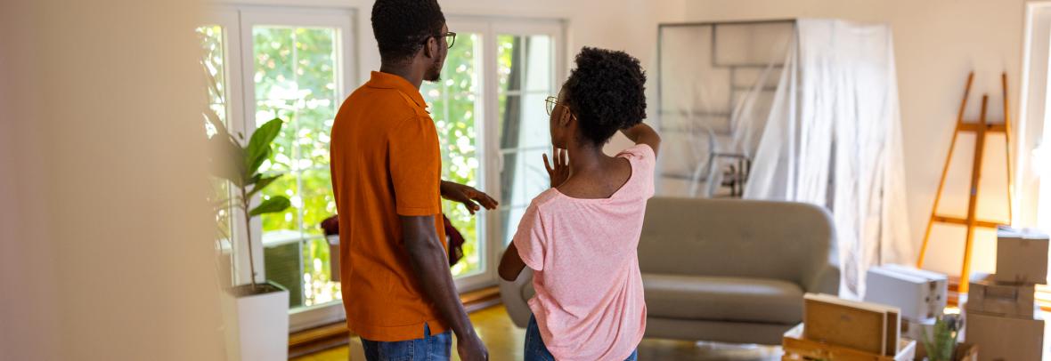 Two people, happy young black couple standing in their new apartment.