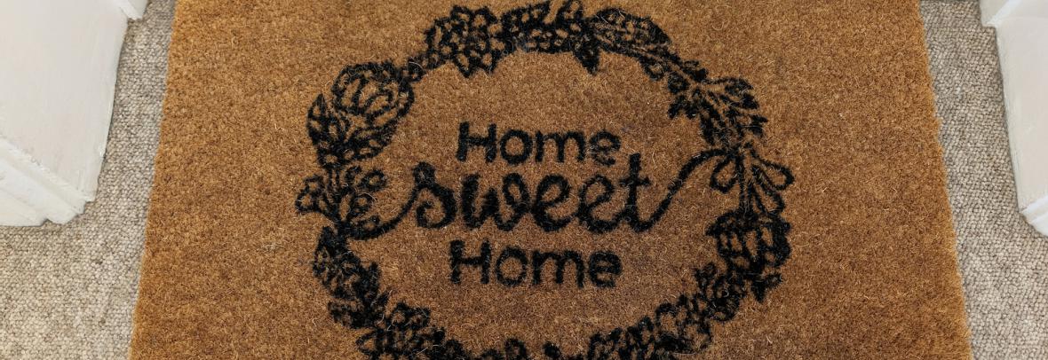 Home Sweet Home welcome mat with shoes at front door