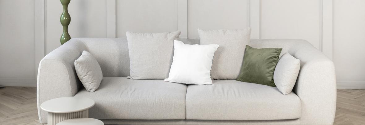 Stylish neutral living room scene featuring a soft beige sofa white cushions, a green floor lamp, and a textured light rug on warm wooden flooring. Demonstrating Pantone color of the year 2026 - Cloud Dancer