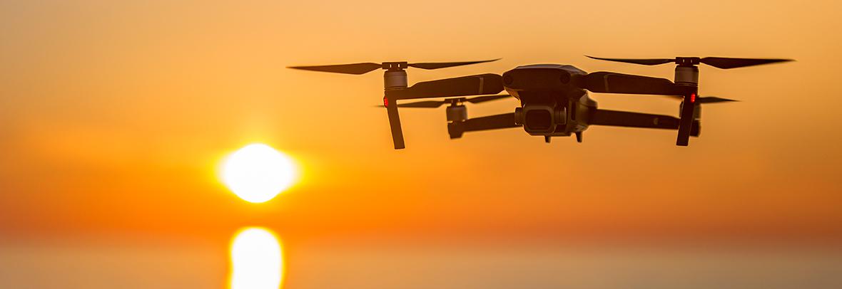 Image of drone flying over a sunset over the ocean