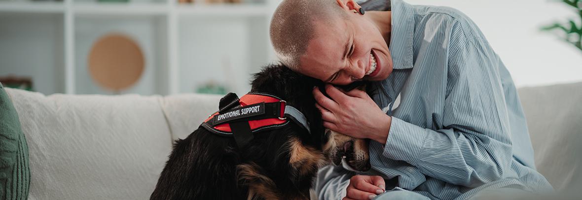 image of a young person hugging emotional support dog on a couch