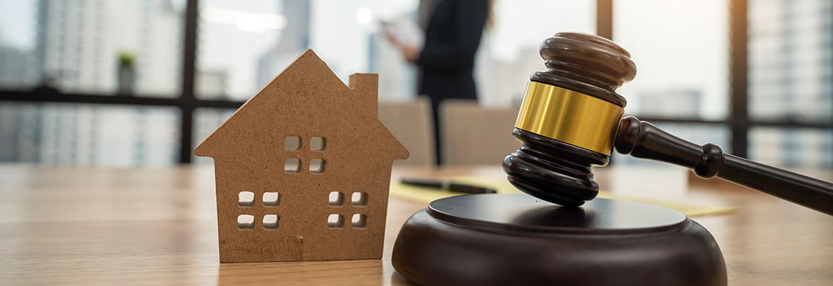 Photo of gavel and wooden house on a desk