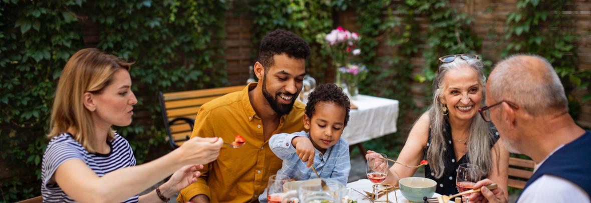 ortrait of multiracial three generations family having dinner together outdoors in front or back yard.