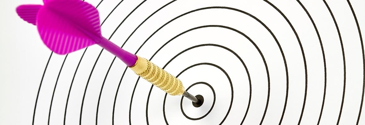 Photo of a dartboard with a pink dark hitting the center