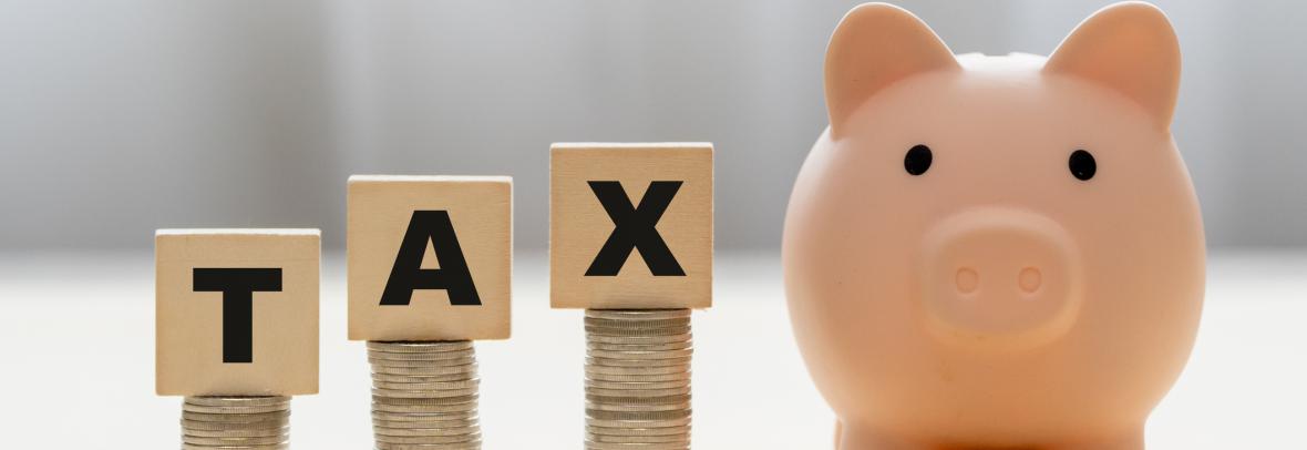 Pink piggy bank and wooden blocks with the word TAX on stack of coins. The concept about saving money and manage time to paying tax. Requesting tax deduction