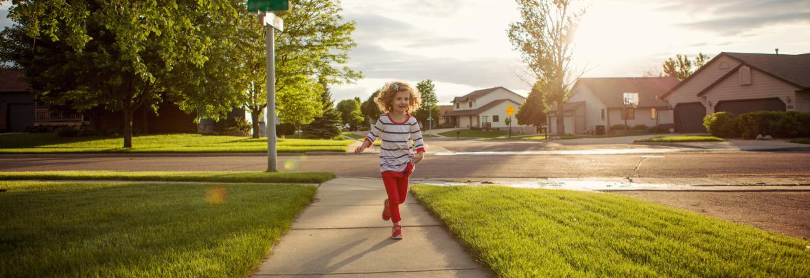 child playing on sidewalk in neighborhood