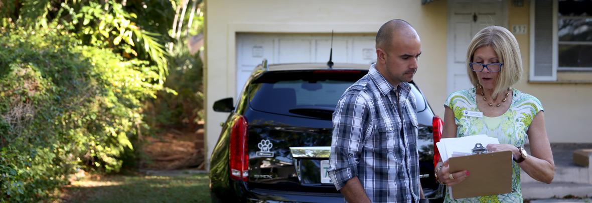 Realtor reviewing paperwork with a client outside a home