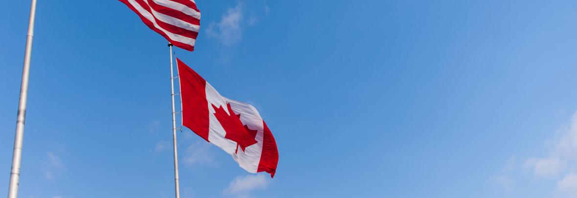 us flag and canadian flag against blue sky