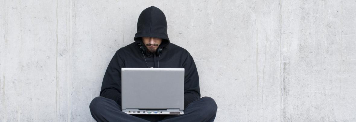 man in hood using computer