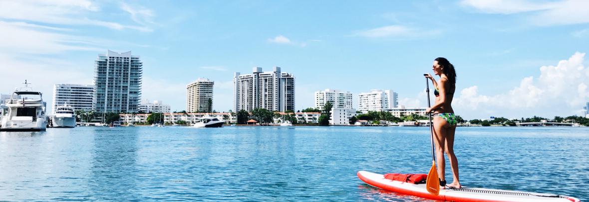 woman paddleboarding with florida skyline in background