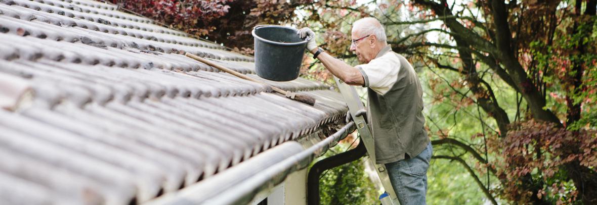man on ladder cleaning gutters