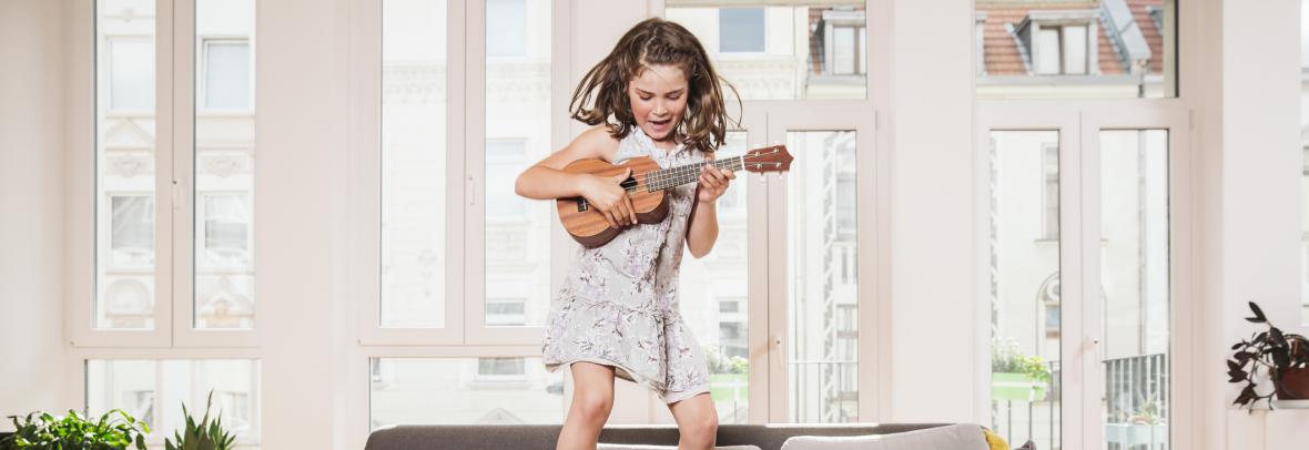 girl with ukelele jumping on couch