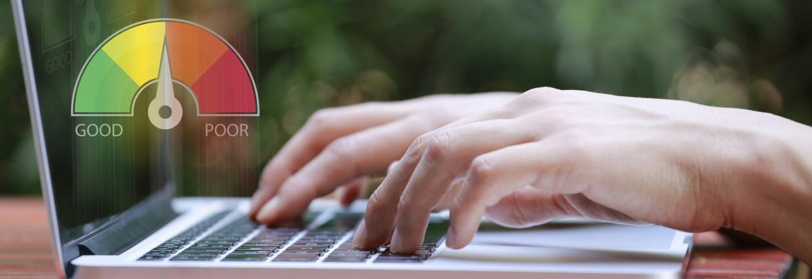 hands typing on laptop with credit score meter