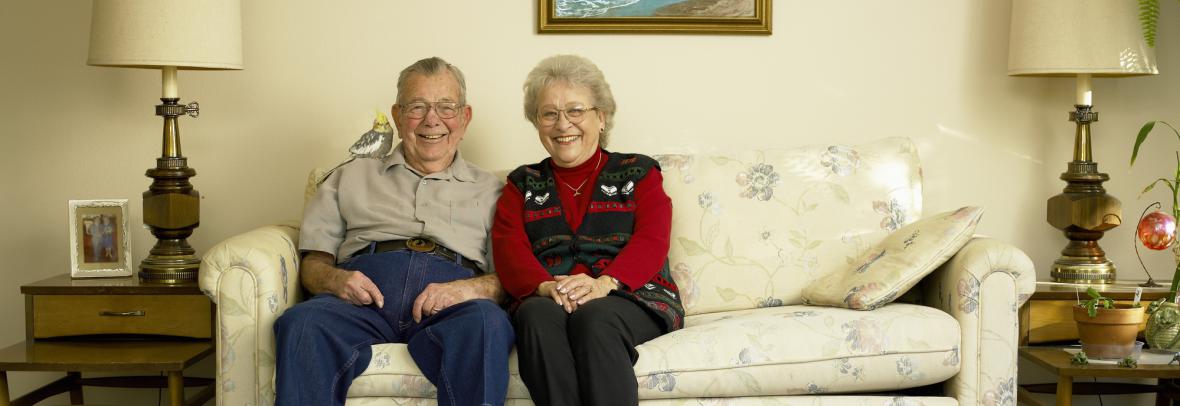 Older couple sitting on couch smiling