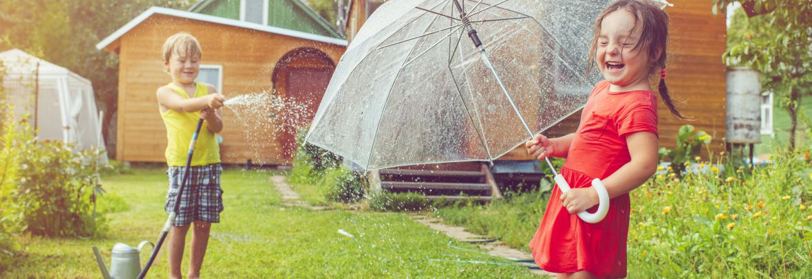children playing outside with umbrella and waterhose