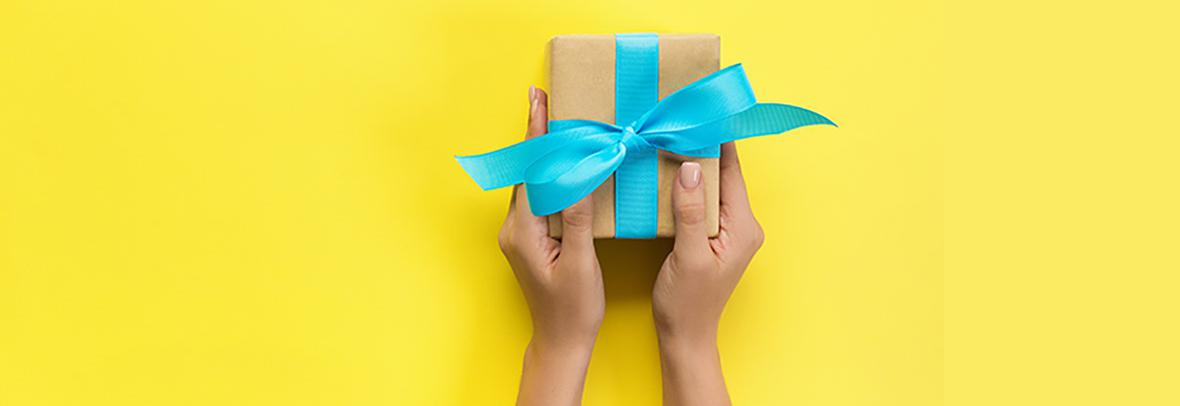 Hands holding gift on yellow background
