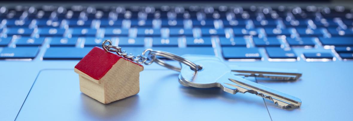 Still life of key ring with a small house and keys on laptop computer