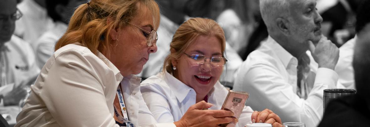 Two women looking a phone during conference