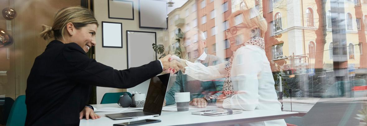 Woman shaking hands with image of another woman in the window