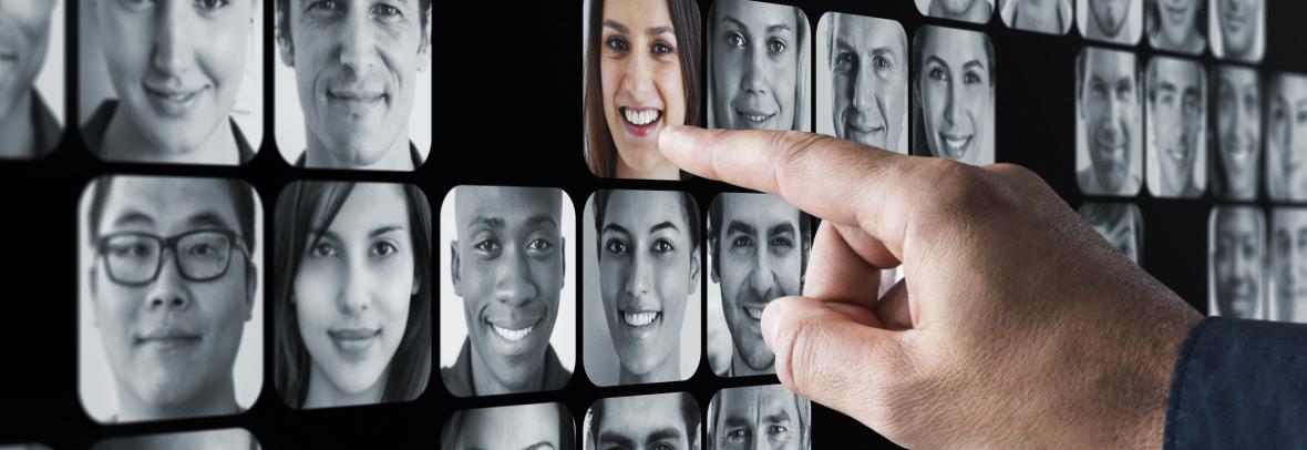 Wall of black and white photos with finger touching only one in color