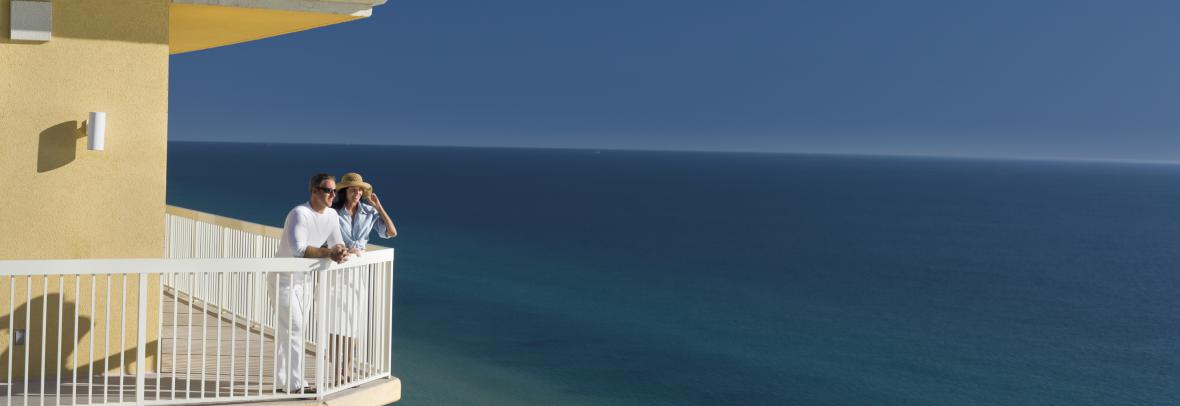 Couple stands on balcony overlooking the ocean