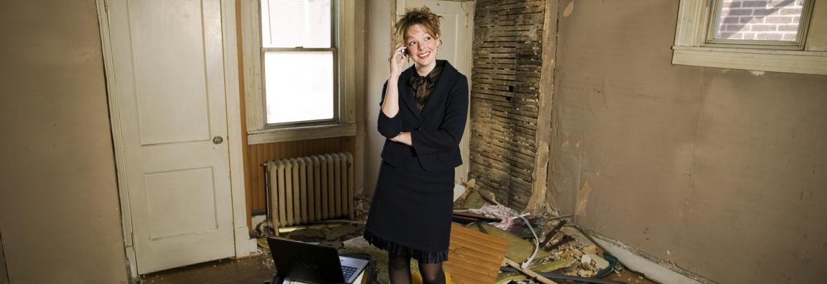 woman standing in rundown house talking on phone