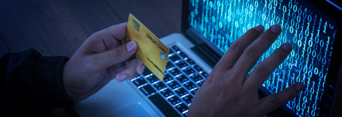 Hand with a credit card hovering in front of a computer screen