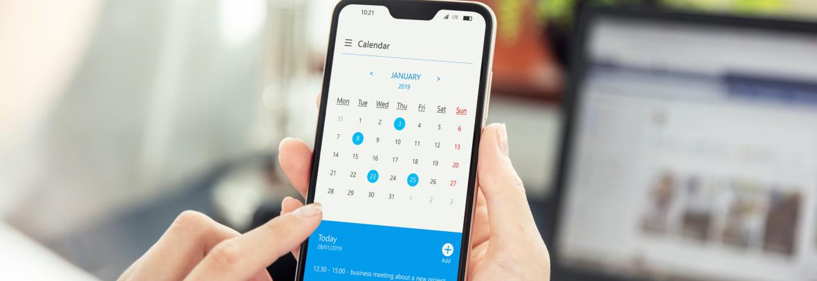 Hands holding phone looking at calendar