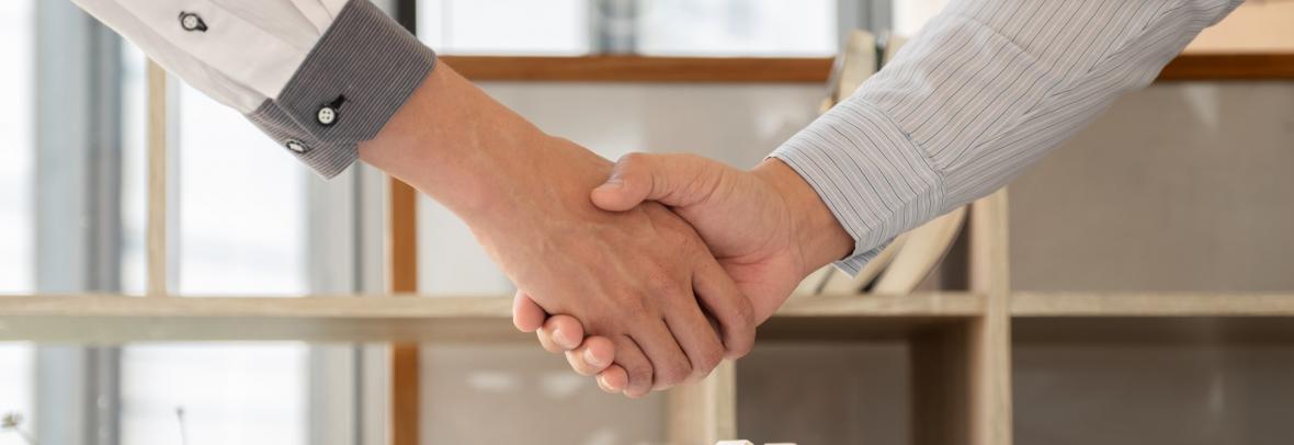 Businessmen and brokers real estate agents catch hand after completing negotiations to buy houses insurance and sign contracts.