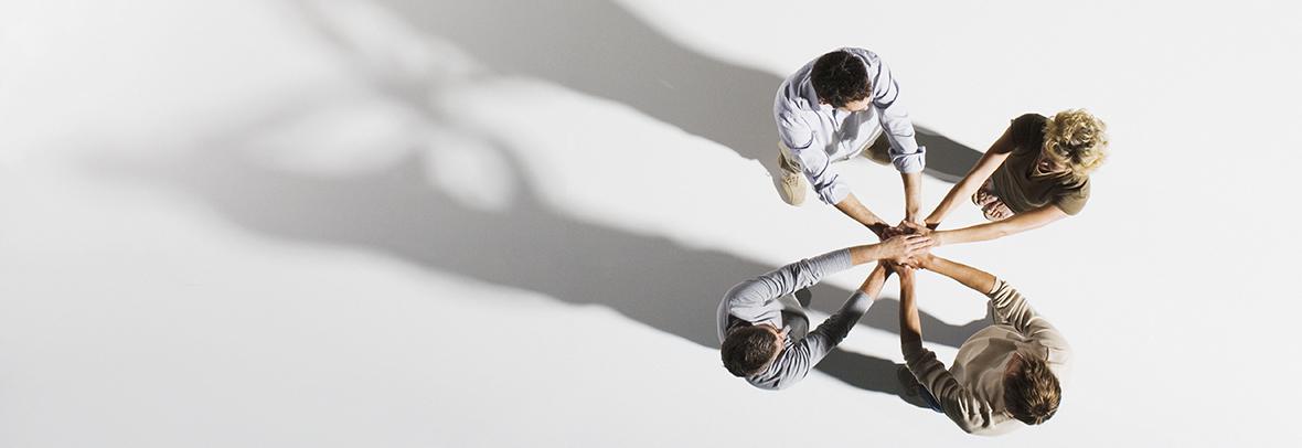 four people with hands on top of each others