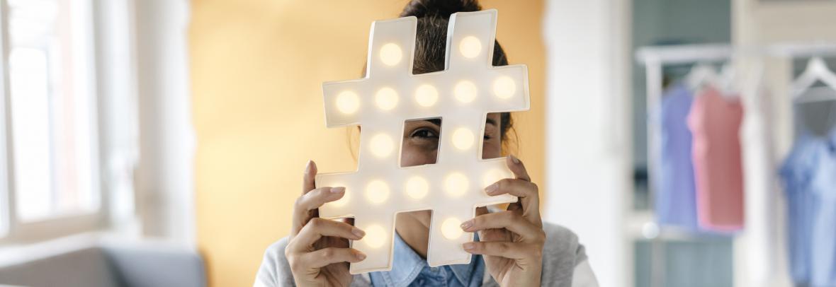 Woman hiding behind big hashtag