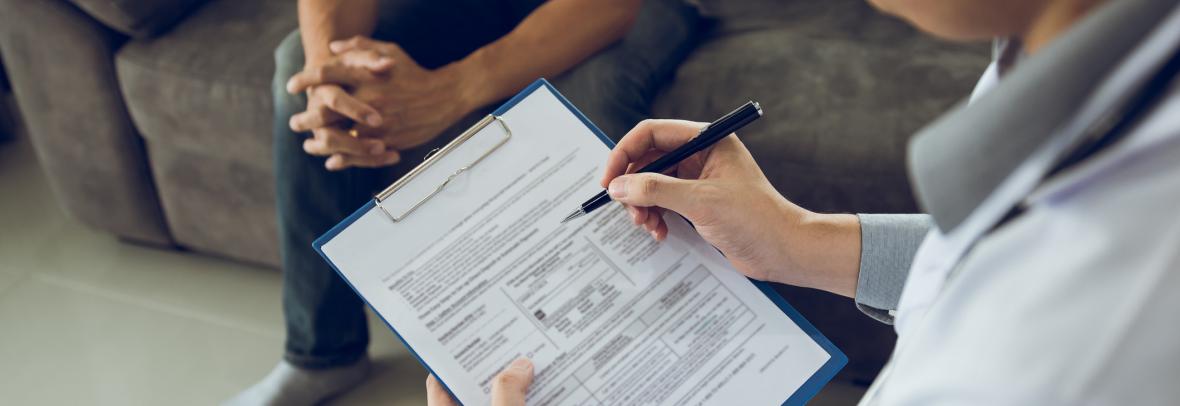 Man with clipboard and paperwork talking to another man