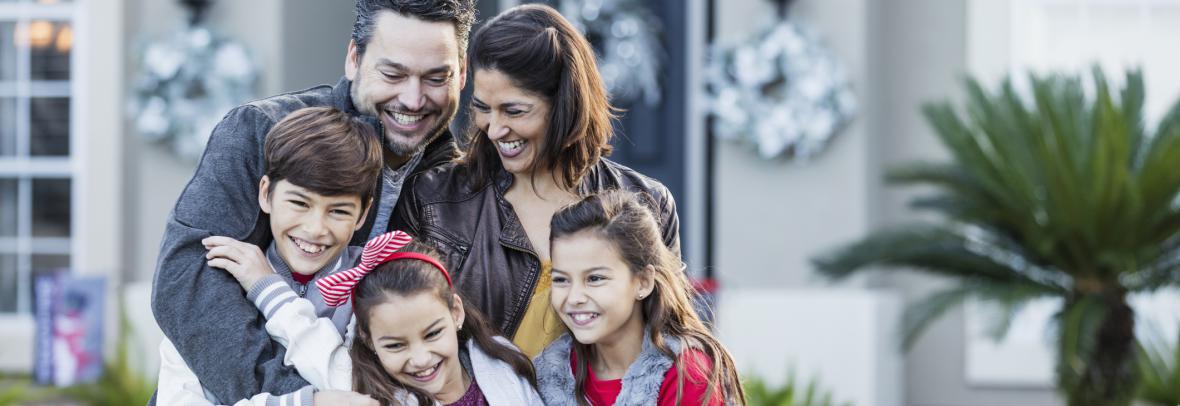 Happy family of five in front of new home